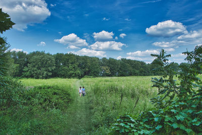 Two females hiking through scenic view of field against sky