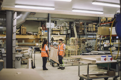 Young blue-collar worker discussing with female colleague in warehouse