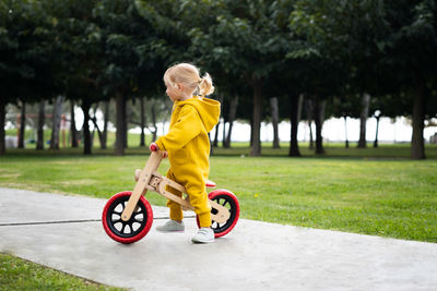 Active cute caucasian baby girl,smiling child about 2 years riding run balance bike in summer park 