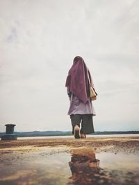 Rear view of woman on beach against sky