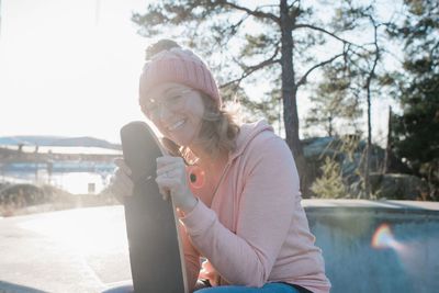 Woman laughing holding her skateboard in a skatepark at sunset