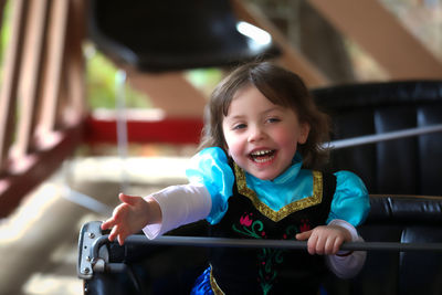 Smiling girl sitting in bumper car at amusement park