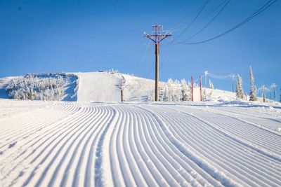 Snow covered landscape against clear blue sky