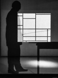 Silhouette person standing against wall