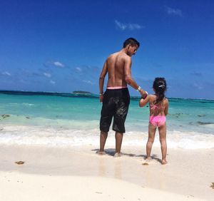 Full length of father and son standing on beach