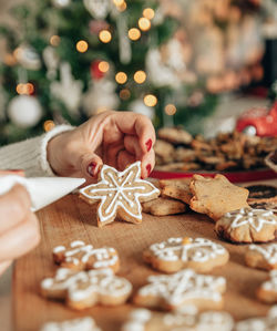 Close-up photo of woman decorating gingerbread christmas cookies at home