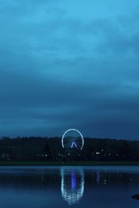 Illuminated ferris wheel by lake at night