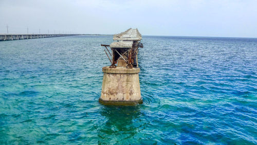 Scenic view of old bridge in sea against sky