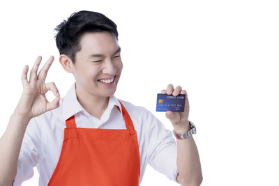 Portrait of smiling young man holding camera over white background