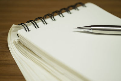 High angle view of pencil on blank note pad at table