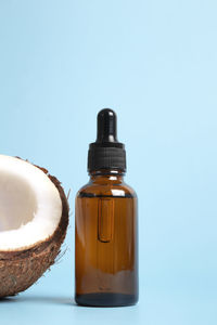 Bottle of coconut oil and fresh coconuts on blue background. coconut natural cosmetics.