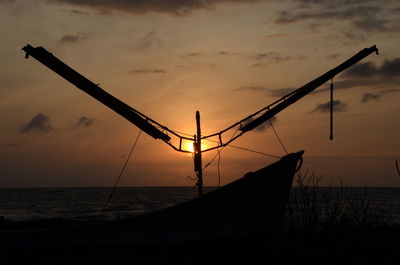 Silhouette sailboat on beach against sky during sunset