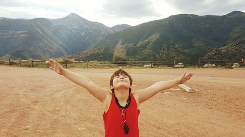 Smiling boy with arms outstretched standing at ranch