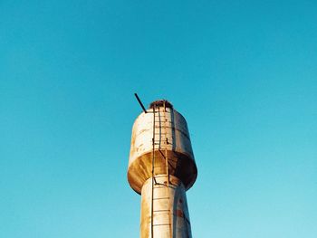 Low angle view of water tower against clear blue sky