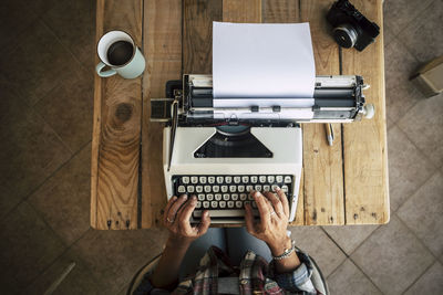 High angle view of woman using typewriter at table