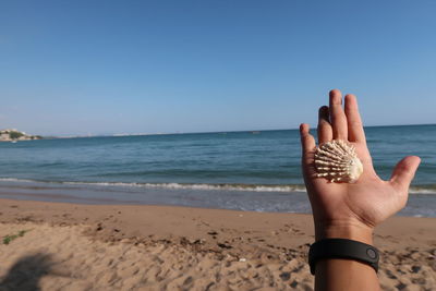 Midsection of woman on beach against clear sky