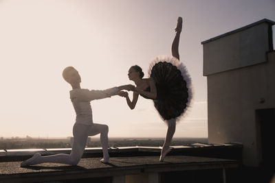 Full length of young woman with arms outstretched against clear sky