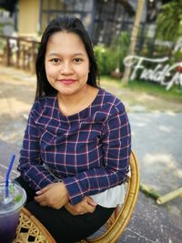 Portrait of smiling woman sitting on chair outdoors