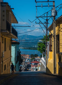 People walking on street amidst buildings in city against sky