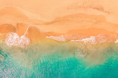 Aerial view of atlantic ocean coast with crystal clear turquoise water, waves rolling into the shore