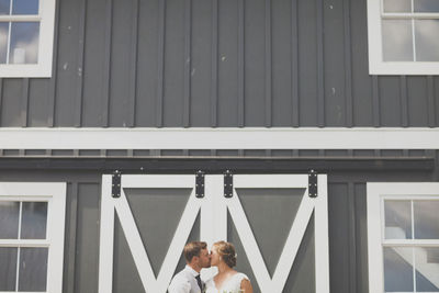 Newlywed young couple kissing against building