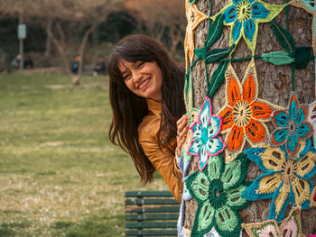 Portrait of young woman hugging a decorated tree