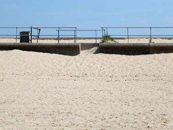 Railing on beach against clear sky