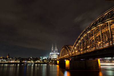 Low angle view of illuminated bridge over river at night