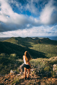 Rear view of woman standing on mountain against sky