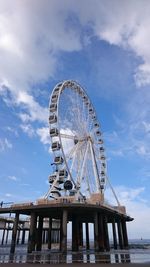 Low angle view of ferris wheel against cloudy sky