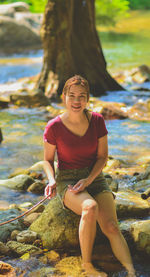 Portrait of a smiling young woman sitting on rock