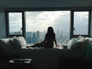 Woman sitting on sofa by window at home