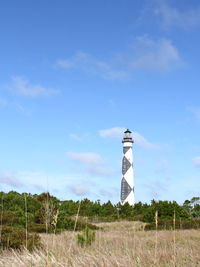 Lighthouse on field against sky