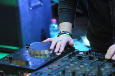 Midsection of man operating sound mixer in club