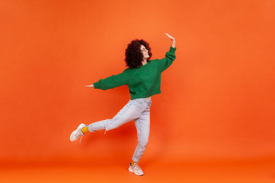 Full length of woman standing against yellow background