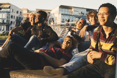 Smiling young and teenage friends enjoying at harbor in city