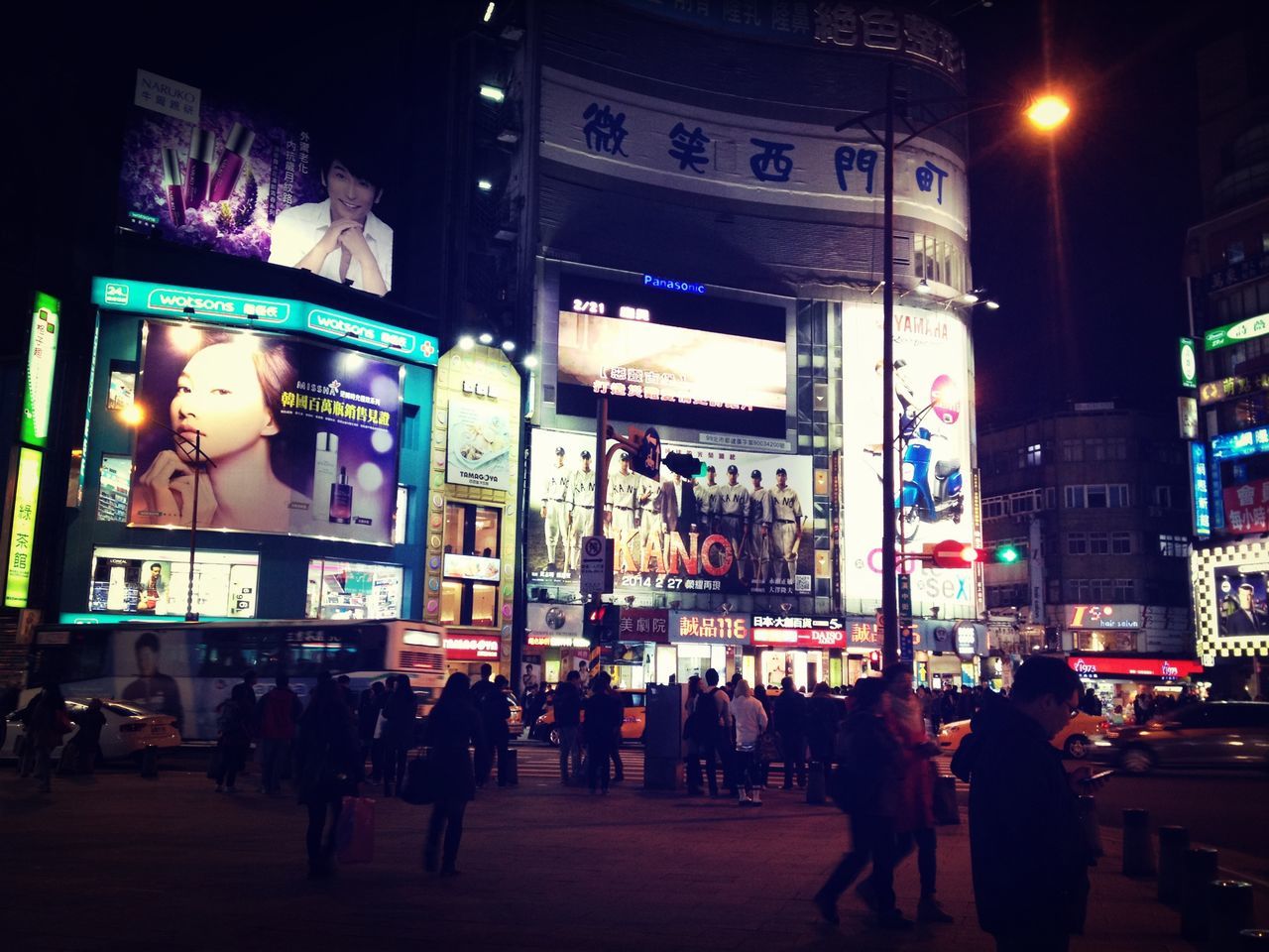 illuminated, large group of people, architecture, built structure, city, night, building exterior, city life, person, men, street, text, lifestyles, walking, city street, advertisement, leisure activity, group of people, commercial sign