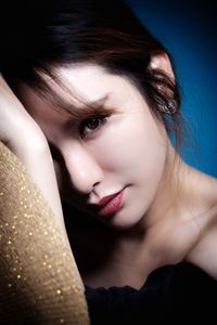 Close-up portrait of beautiful woman against blue background