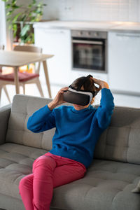 Young woman puts on vr glasses for first time and prepares to play interesting games at home