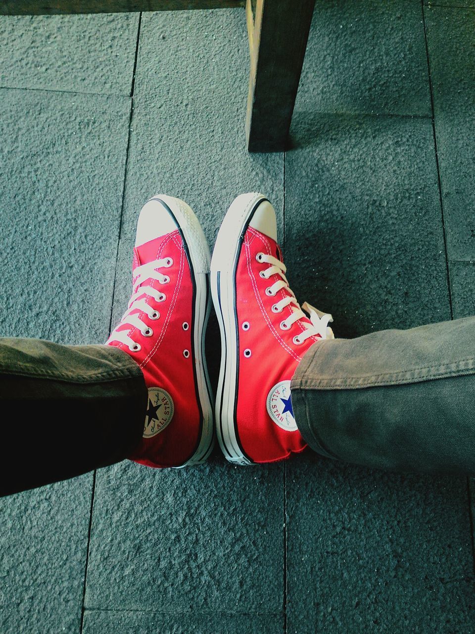 low section, shoe, person, footwear, red, high angle view, street, human foot, pair, canvas shoe, flooring, jeans, close-up, personal perspective, tiled floor, indoors, standing, pattern, day, shadow