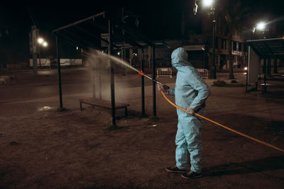 Rear view of man standing on illuminated street at night