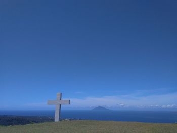 Cross on field against blue sky