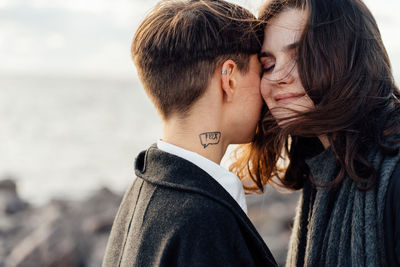 Side view of couple kissing against sea