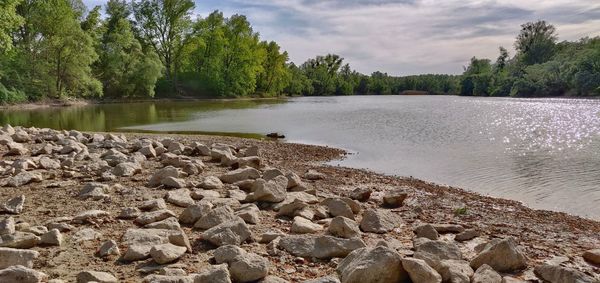 Rocks by lake against sky