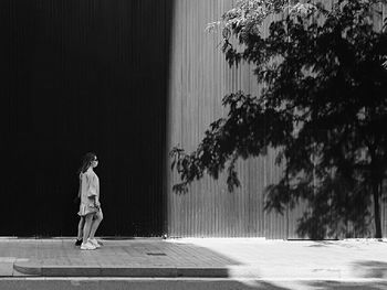 Full length of woman standing on footpath against trees