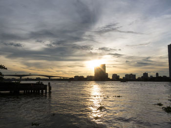 Scenic view of sea by buildings against sky during sunset