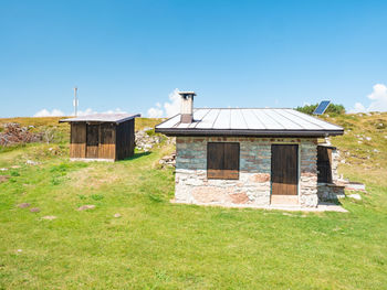 House on field against clear blue sky