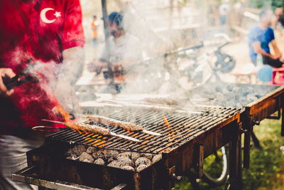 Midsection of man preparing barbecue on grill at market