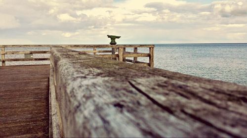 Pier on sea against cloudy sky