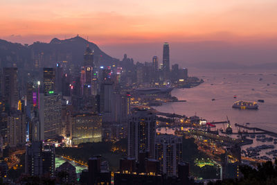 Illuminated modern buildings in city against sky during sunset